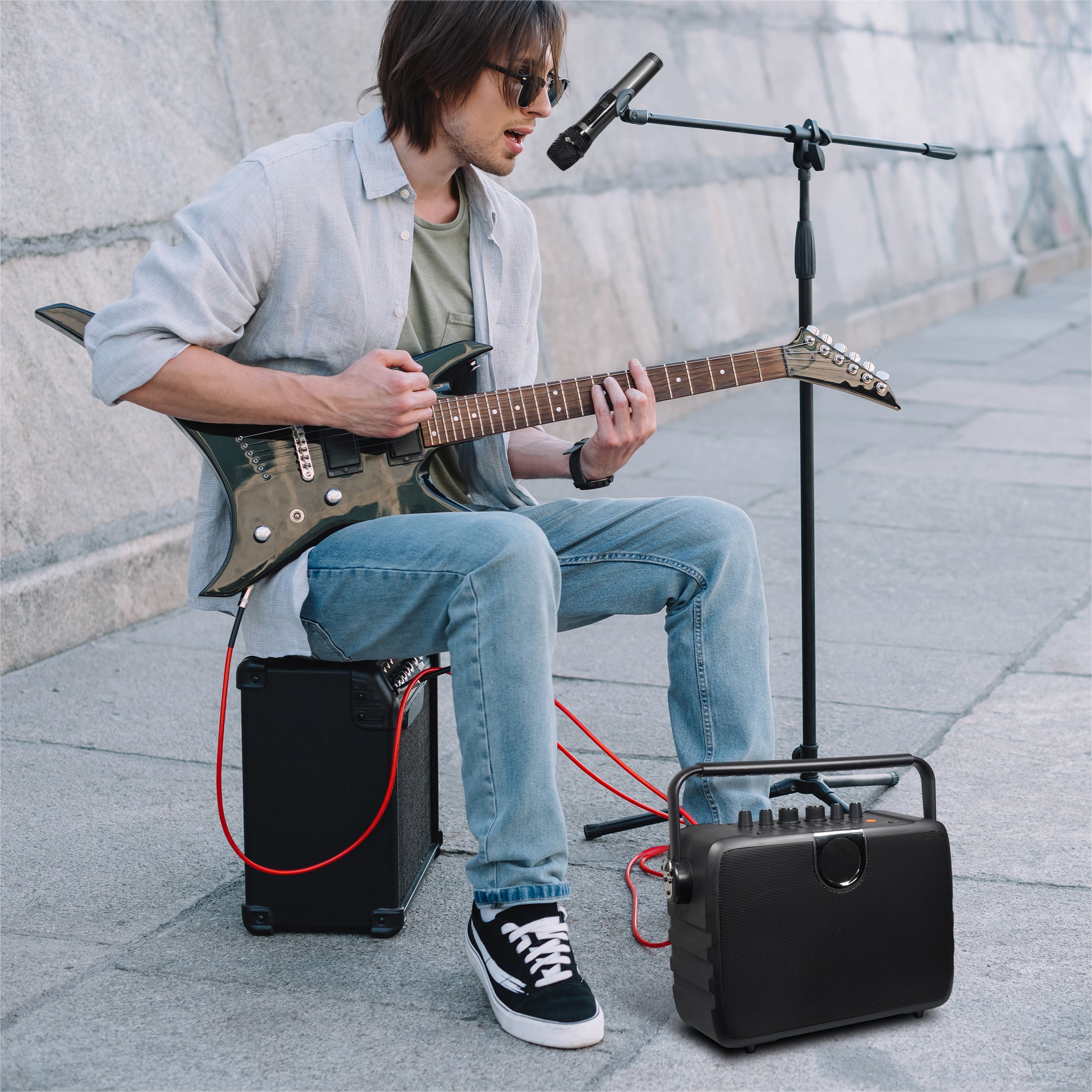 Young happy busker playing guitar and singing at city street